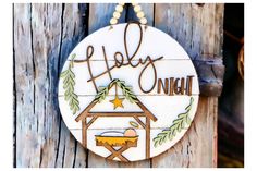 a christmas ornament hanging on the side of a wooden fence with a nativity scene