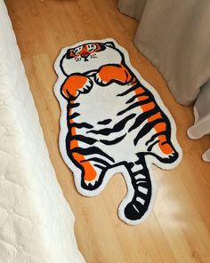 a tiger rug sitting on top of a hard wood floor next to a white bed