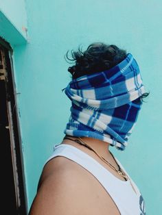 a woman with a bandana on her head standing in front of a blue wall