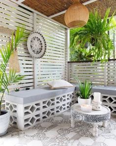 an outdoor living area with white furniture and potted plants on the wall, along with wicker roofing