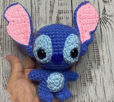 a small blue and pink crocheted stuffed animal with big ears on it's head