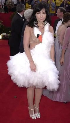 a woman in a white dress standing on a red carpet