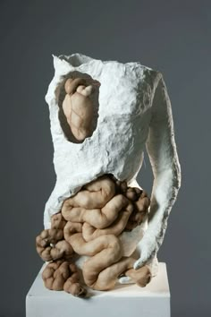 the sculpture is made out of clay and has been placed on top of a white pedestal