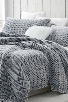 a bed covered in grey and white blankets