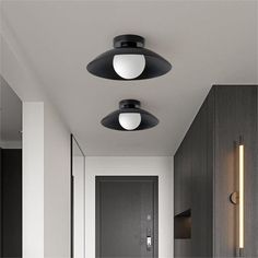 two black lights are hanging from the ceiling above a white hallway with dark wood paneling