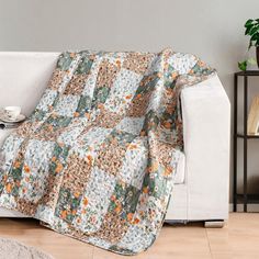 a living room with a white couch covered in a blanket and coffee cup on the end table