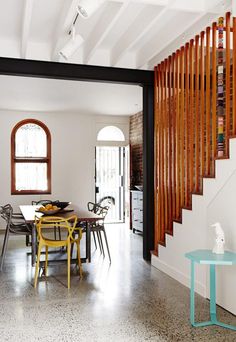 a dining room table and chairs in front of a stair case with wooden slats