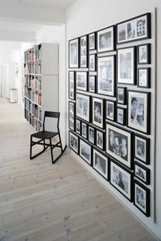 a room with many pictures on the wall and a chair in front of it next to a bookshelf