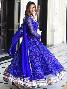 An ethereal, elegant and evergreen outfit! Our blue chiffon bandhani gown is a must-have.A flared bandhani gown with gota lace accents on the neck and sleeves & duppta a beautiful hand made latkam makes this outfit perfect for every occasion.  Size-36 to 44 Plus size 46 to 64 Traditional Blue Dress With Sheer Dupatta, Bandhani Gown Design, Blue Bandhani Dress, Festive Maxi Dress With Sheer Dupatta For Navratri, Bollywood Georgette Maxi Dress With Dupatta, Blue Dresses With Mirror Work For Diwali, Bollywood Maxi Dress With Sheer Dupatta For Festivals, Blue Dress With Sheer Dupatta For Festivals, Blue Long Gown For Festive Occasions