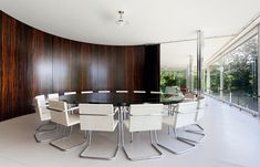 a dining room table with white chairs in front of a large wooden paneled wall