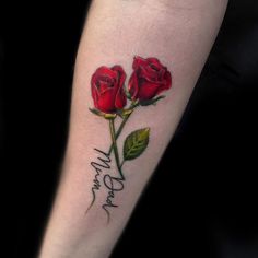 a woman's arm with two red roses and the word love tattooed on it