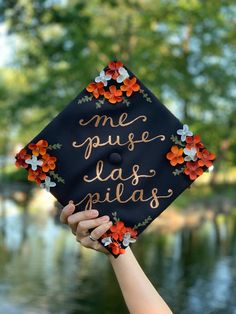 a person holding up a graduation cap with flowers on it