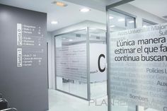 the entrance to an office building with large glass doors and signs on the side wall