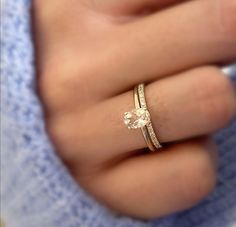 a woman's hand wearing a gold ring with a diamond on the middle finger