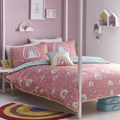 a bed with pink sheets and rainbows on it in a child's bedroom