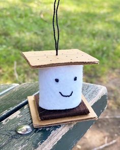 a cup with a smiley face on it sitting on top of a wooden table in the grass