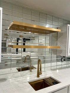 a kitchen with white counter tops and stainless steel shelving above the sink, along with a gold faucet