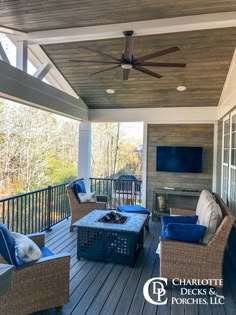 an outdoor living area with wicker furniture and ceiling fan on the deck overlooking trees