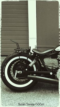 a black and white photo of a motorcycle parked in front of a garage with the door open