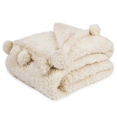 a white teddy bear blanket folded on top of each other with pom - poms