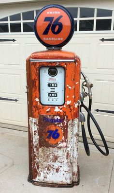 an old rusty gas pump sitting in front of a garage door with the number seventy on it