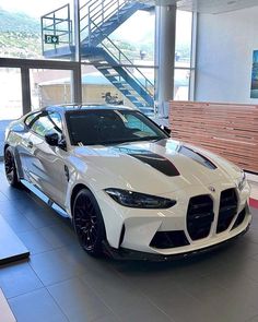 a white sports car parked in a showroom with stairs leading up to the top