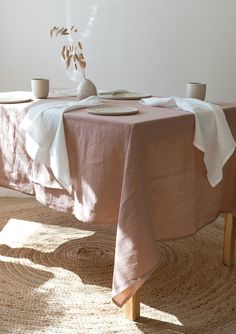 the table is set with two cups and plates on it, along with an empty vase