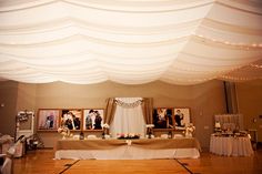 an image of a wedding reception setup with pictures on the wall and lights hanging from the ceiling