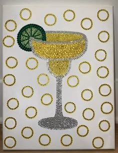 a painting with beads on it that has a yellow drink in the glass and a lime