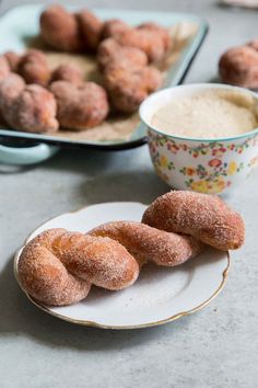 doughnuts are sitting on plates next to a bowl of dip