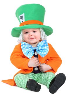 a small child wearing a green top hat and bow tie sitting on the ground with his hands in his pockets