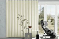 a living room filled with furniture and a large window covered in white drapes