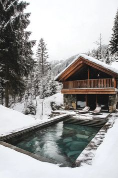 a cabin with a hot tub in the foreground and snow on the ground around it