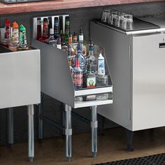 an open cabinet with bottles and glasses in it next to a counter full of liquor