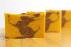 two pieces of yellow and brown soap sitting on top of a wooden table next to each other