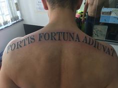 the back of a man's upper body with words written on his left shoulder