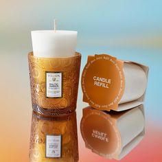 an orange candle sitting next to a box with a label on it that says candle refill