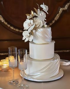 a wedding cake with white flowers and candles