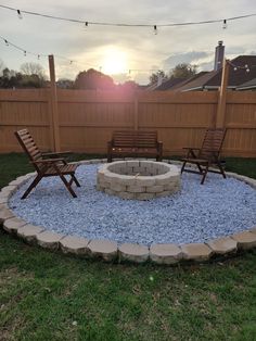 an outdoor fire pit surrounded by chairs and gravel