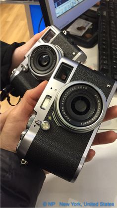 a person holding an old camera in front of a computer