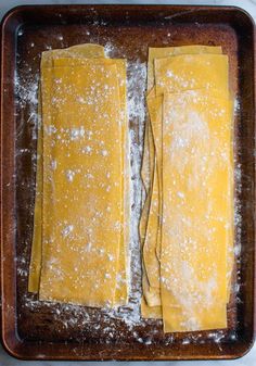 two uncooked pizza doughs sitting on top of a baking pan covered in powdered sugar