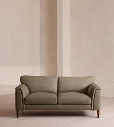 a beige couch sitting on top of a hard wood floor next to a white wall