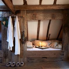 a bed in a room with wooden walls and beams on the ceiling is lit by a candle