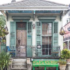 a green bench sitting in front of a building with shutters on the doors and windows