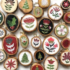 several different types of embroidered ornaments on wood slices with flowers and leaves painted on them