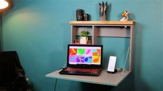 a laptop computer sitting on top of a wooden desk next to a book shelf and lamp