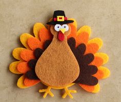 a felt turkey with a pilgrim hat on it's head is sitting in front of a brown background