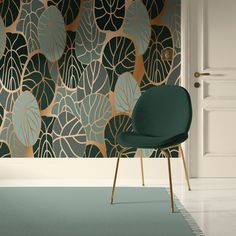 a green chair sitting in front of a wall with gold and blue leaves on it