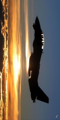 an airplane flying in the sky at sunset