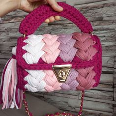 a hand holding a pink and white purse